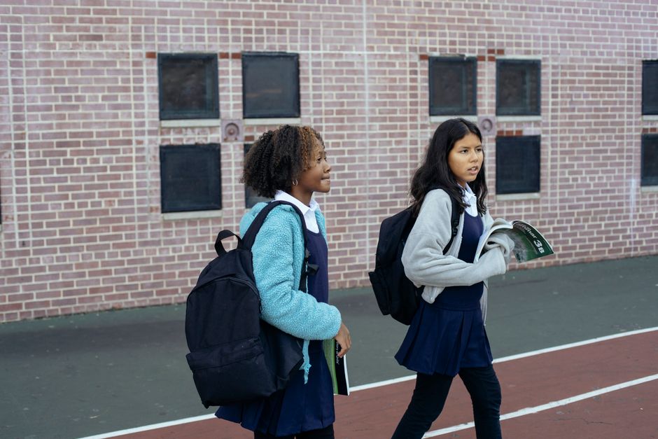 A Year 6 student in uniform walking into a Victorian secondary school with a backpack, looking a little nervous and a little excited.